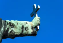 socha držící křesťanský kříž