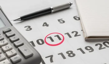 kalendář se zakroužkovanou 11, vedle propiska a kalkulačka