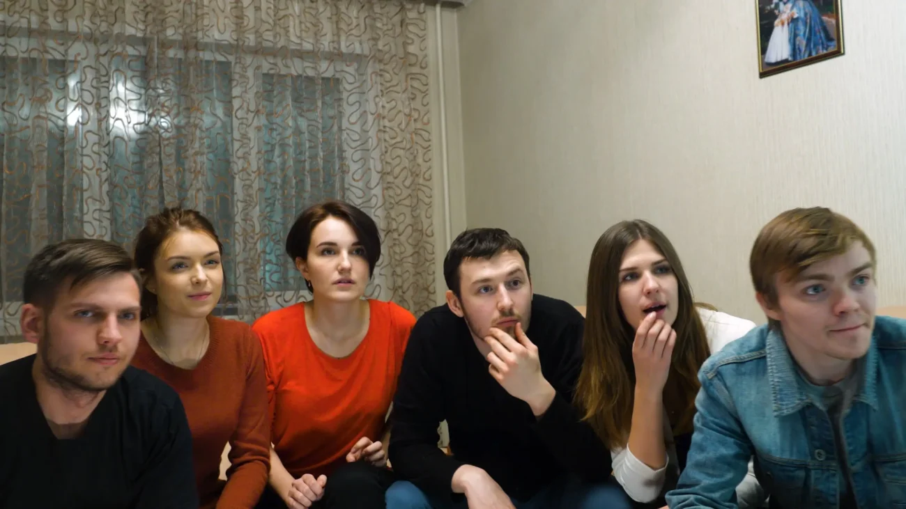 Mladí lidé vedle sebe sedí na gauči.