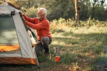 Starší muž staví stan.