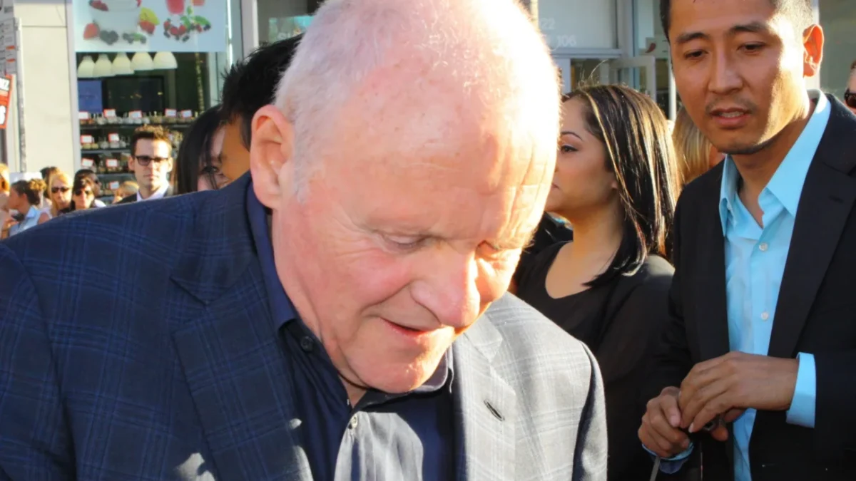 Anthony Hopkins stojí se skloněnou hlavou.