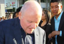 Anthony Hopkins stojí se skloněnou hlavou.