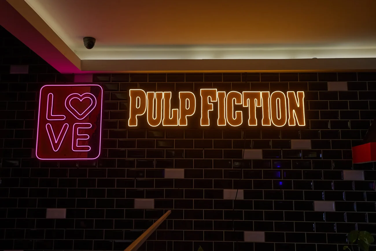 shutterstock_2459852295-2 | TVGURU.cz Na zdi svítí nápis Pulp Fiction.