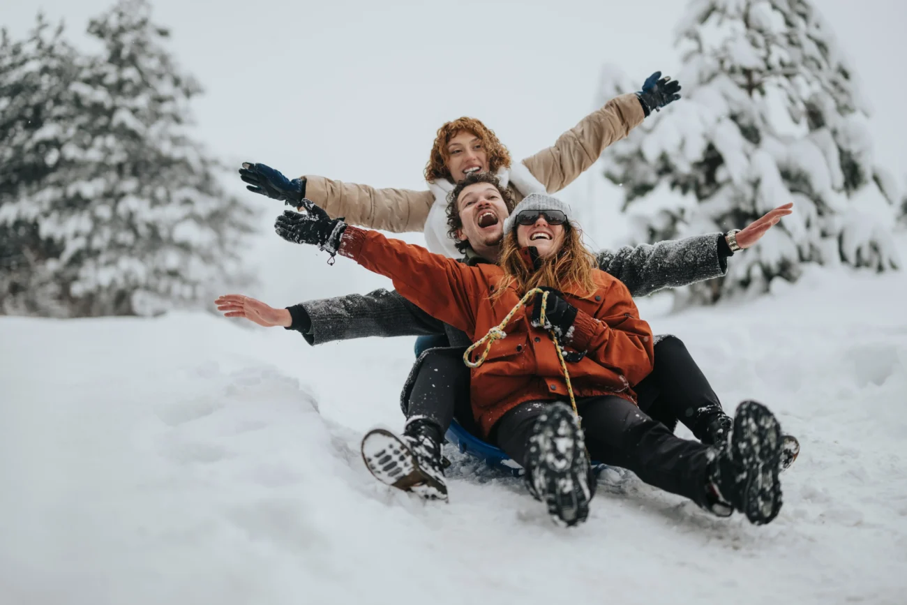 shutterstock_2610348323 1 | TVGURU.cz Mladí lidé jedou na saních z kopce.