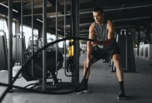 Muž cvičí s posilovacím lanem.