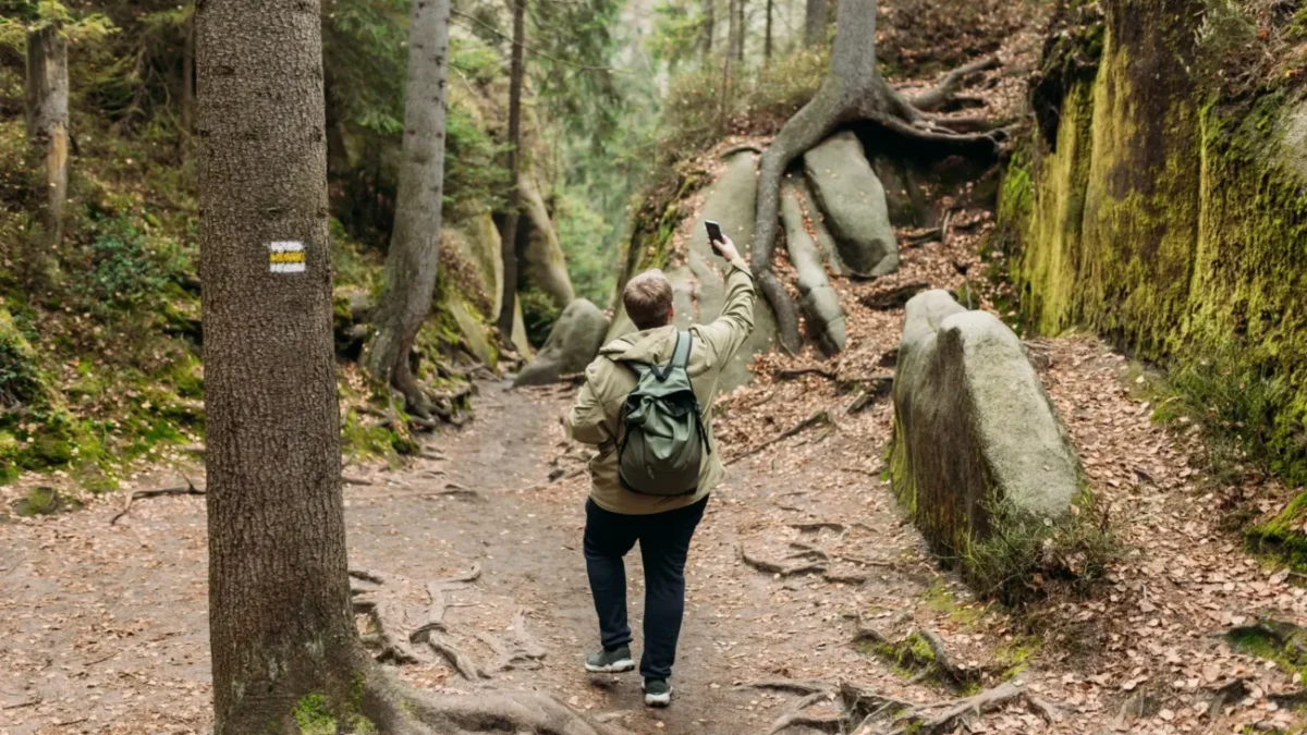 muž v lese hledá signál na telefonu