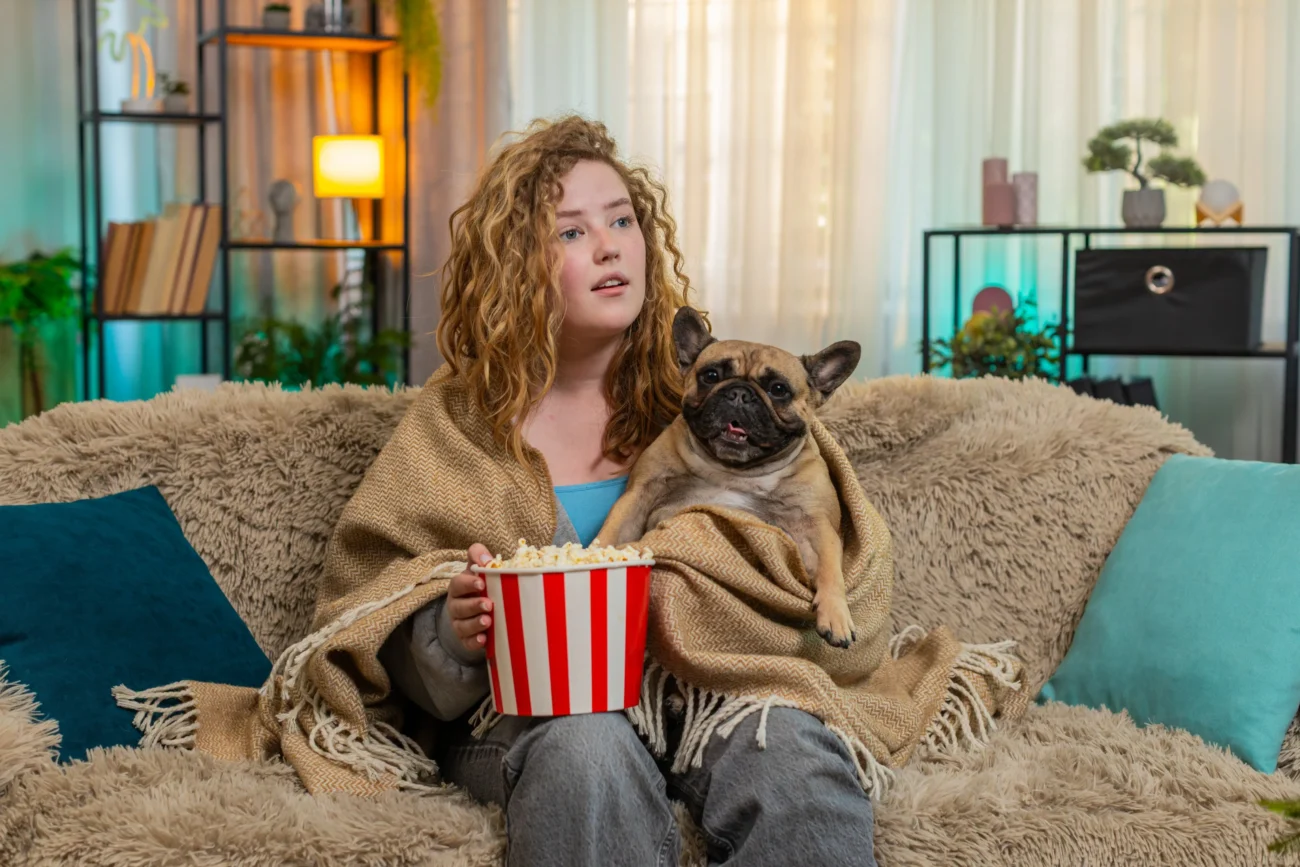 shutterstock_2624908201 1 | TVGURU.cz Žena sedí na gauči s popcornem a psem.