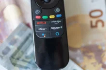 ovladač ležící na penězích, s tlačítkem Rakuten TV