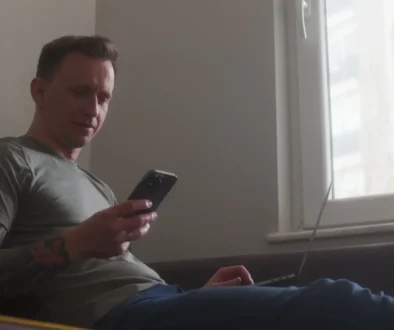 muž kouká do telefonu a počítače