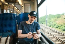 Mladý muž cestuje vlakem a v uších má sluchátka.