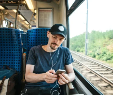 Mladý muž cestuje vlakem a v uších má sluchátka.