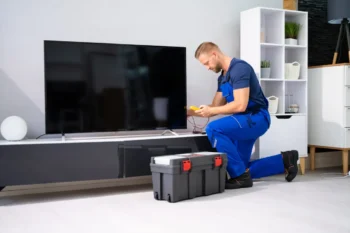 Technik klečí u televize.