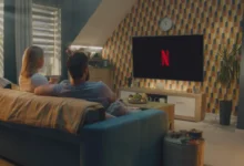 Dva lidé sedí na gauči a koukají na Netflix.