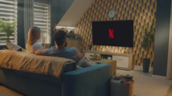Dva lidé sedí na gauči a koukají na Netflix.