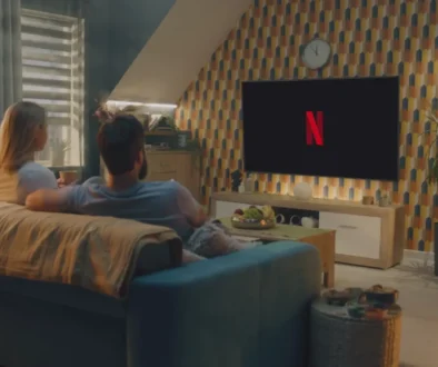 Dva lidé sedí na gauči a koukají na Netflix.