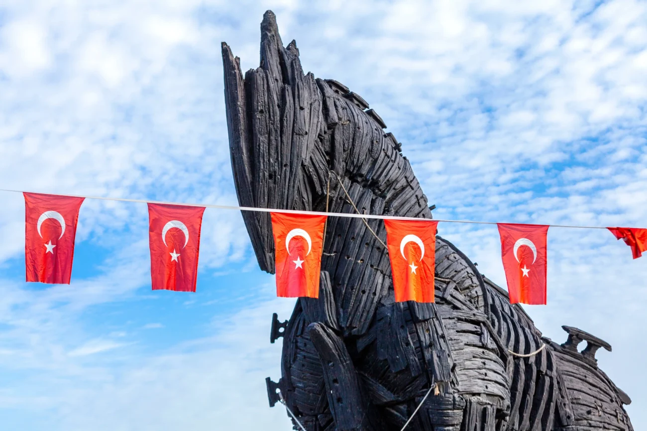 shutterstock_2598713311-2 | TVGURU.cz Před dřevěnou sochou visí turecké vlajky.
