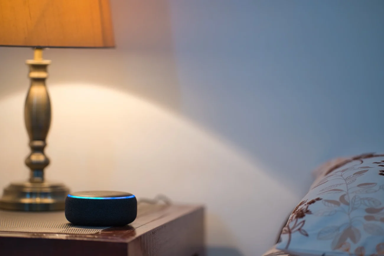Chytrý asistent do domácnosti stojí na nočním stolku.