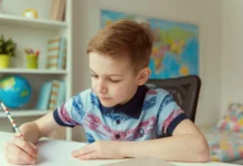 Chlapeček sedí u stolu a píše.