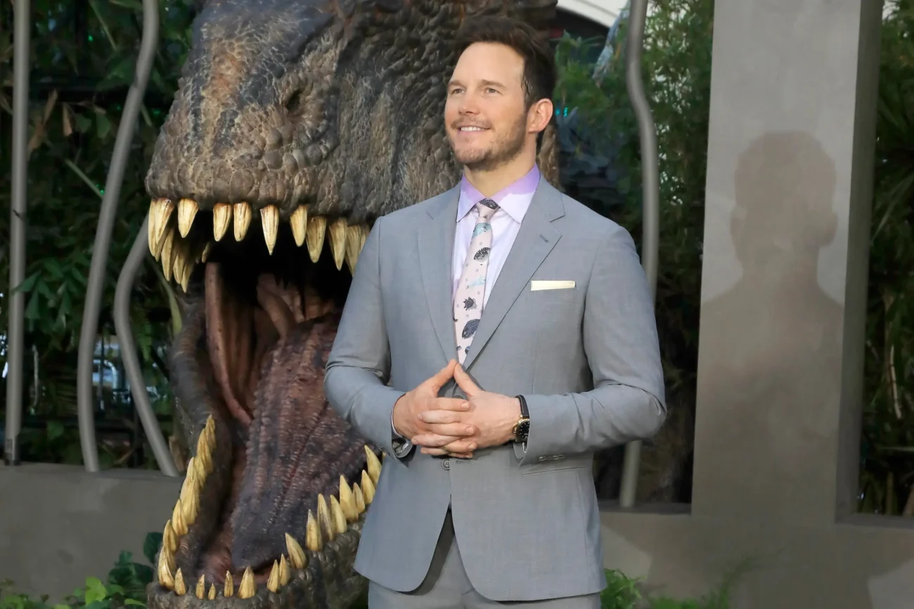 Chris Pratt stojí u tlamy dinosaura. 