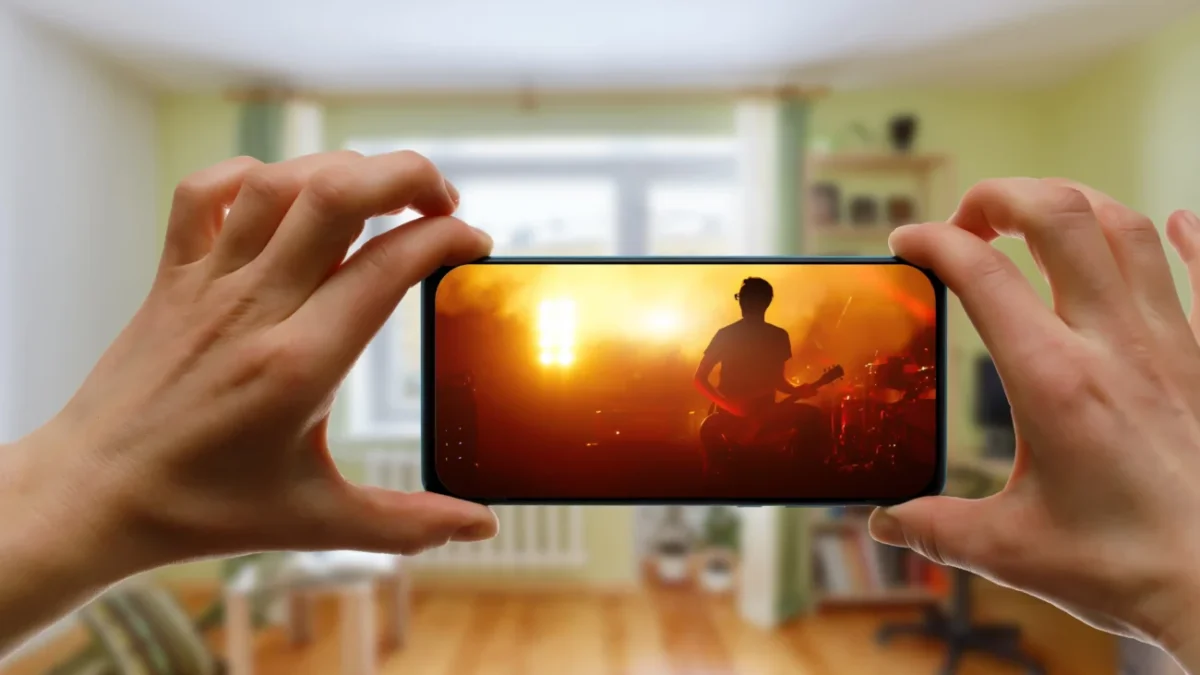 Člověk v ruce drží telefon, na kterém je puštěný hudební videoklip.