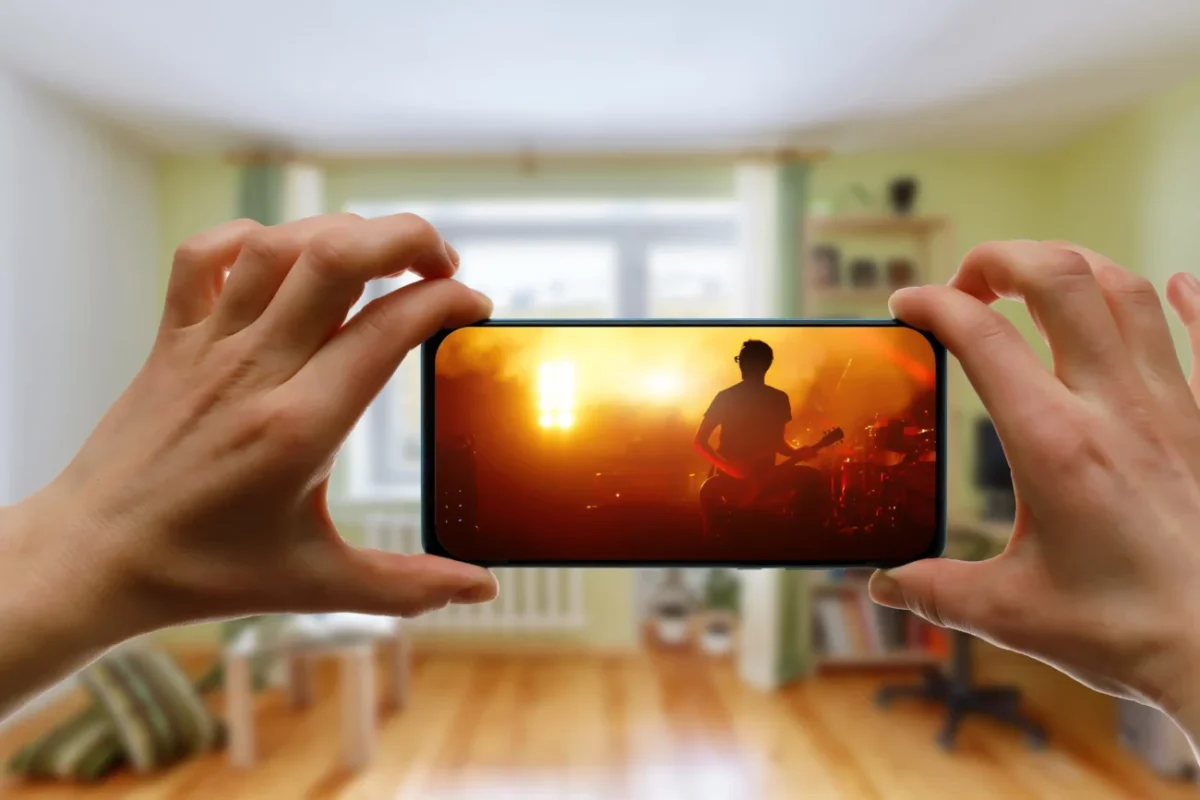 Člověk v ruce drží telefon, na kterém je puštěný hudební videoklip.