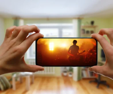 Člověk v ruce drží telefon, na kterém je puštěný hudební videoklip.