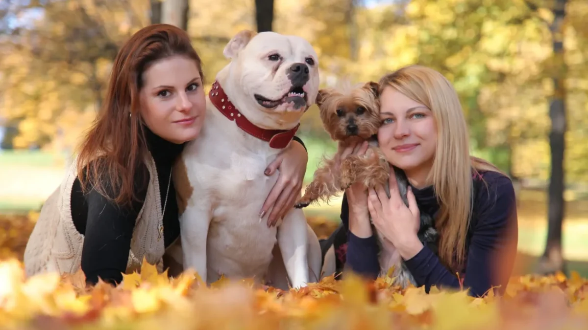 Dvě ženy se v parku fotí s velkým a malým psem.