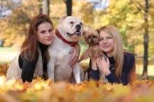 Dvě ženy se v parku fotí s velkým a malým psem.