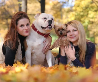 Dvě ženy se v parku fotí s velkým a malým psem.