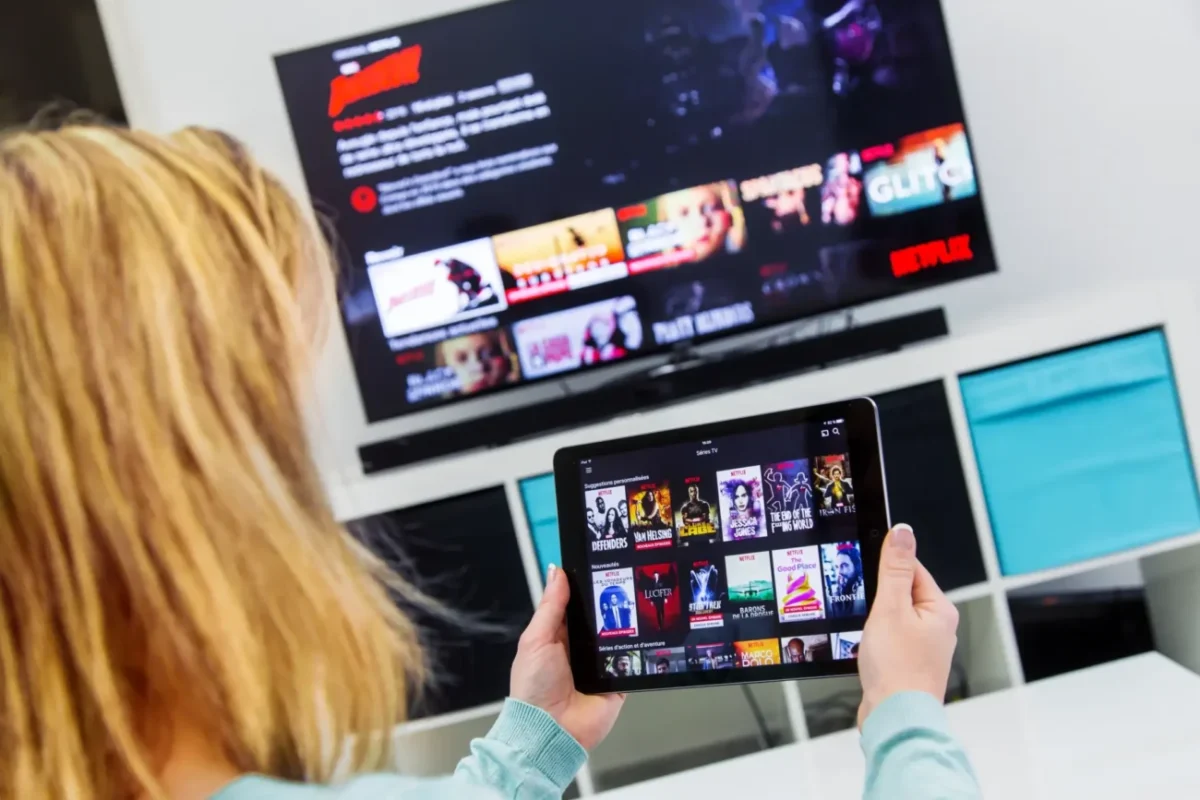 Žena má Netflix spuštěný na televizi i tabletu.