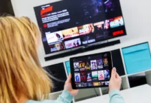 Žena má Netflix spuštěný na televizi i tabletu.