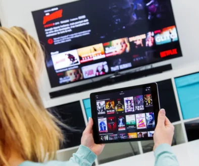 Žena má Netflix spuštěný na televizi i tabletu.