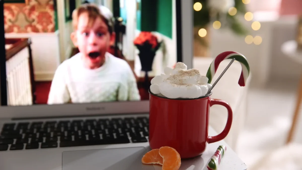 Na notebooku stojí hrnek s kakaem a hraje Sám doma.