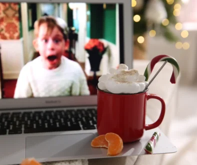 Na notebooku stojí hrnek s kakaem a hraje Sám doma.