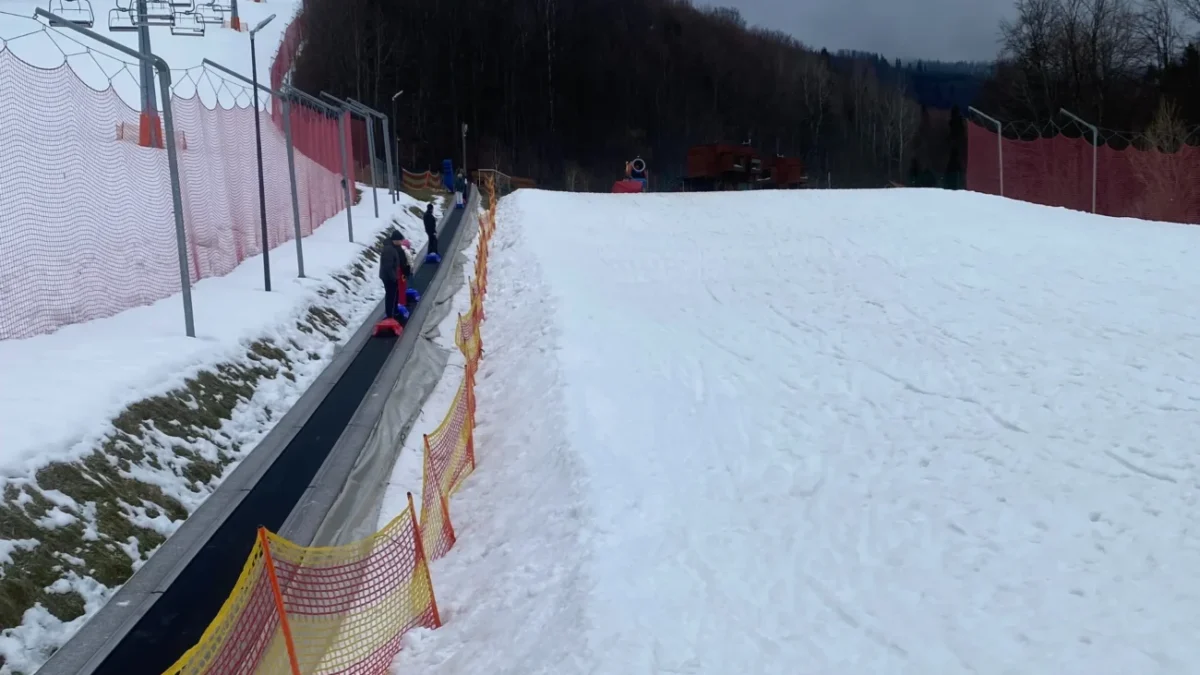 lidé jsou na horách na zasněženém kopci a jedou sáňkovat