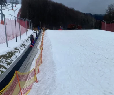 lidé jsou na horách na zasněženém kopci a jedou sáňkovat