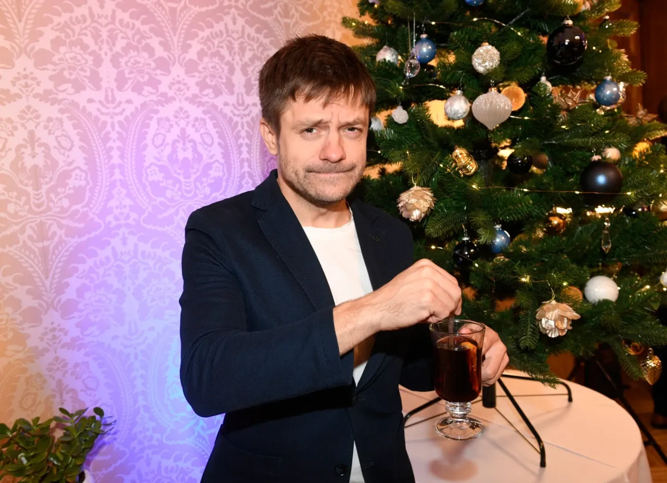 Jiří Mádl stojí před vánočním stromečkem. 