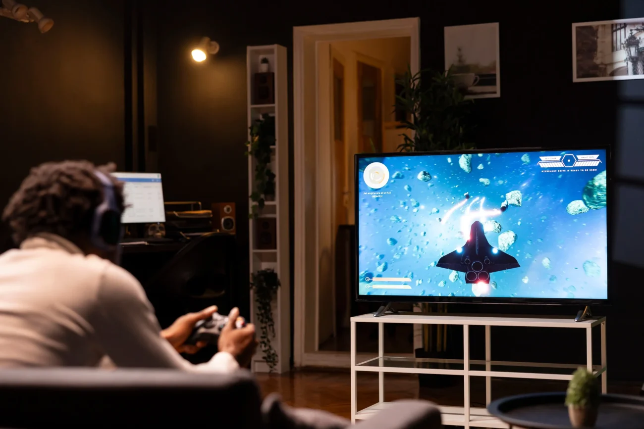 Muž sedí na gauči a hraje online hry.