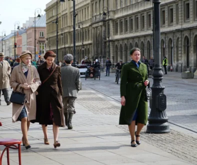 Dobově oblečené ženy se procházejí ulicemi.