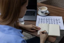 Žena sedí u stolu a píše si čísla do notesu.