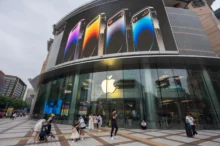 Před čínskou prodejnou Applu chodí lidé.