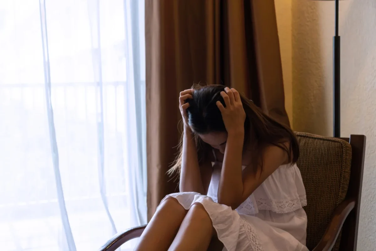 Žena sedí skleslá na křesle.