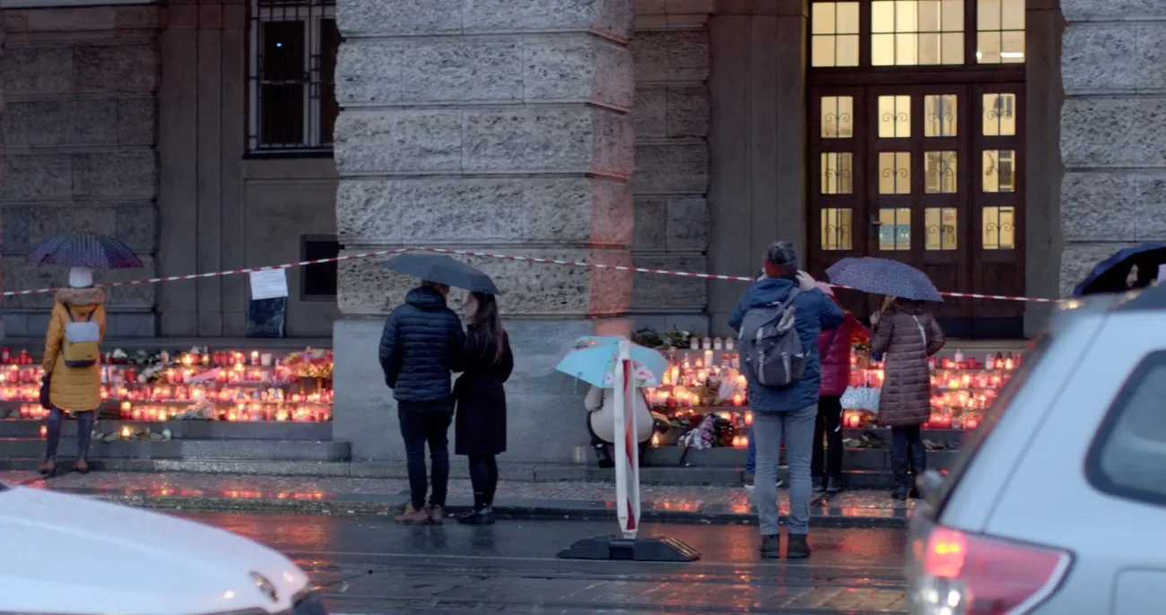 pozůstalí zapalují svíčky před uměleckou fakultou, jako připomínku obětí střeleckého útoku v PRaze
