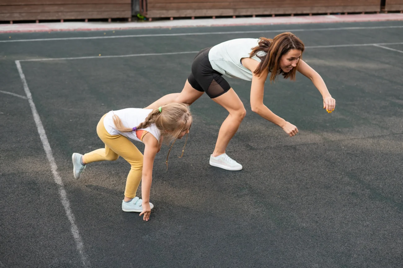 Žena s holčičkou cvičí na hřišti. 