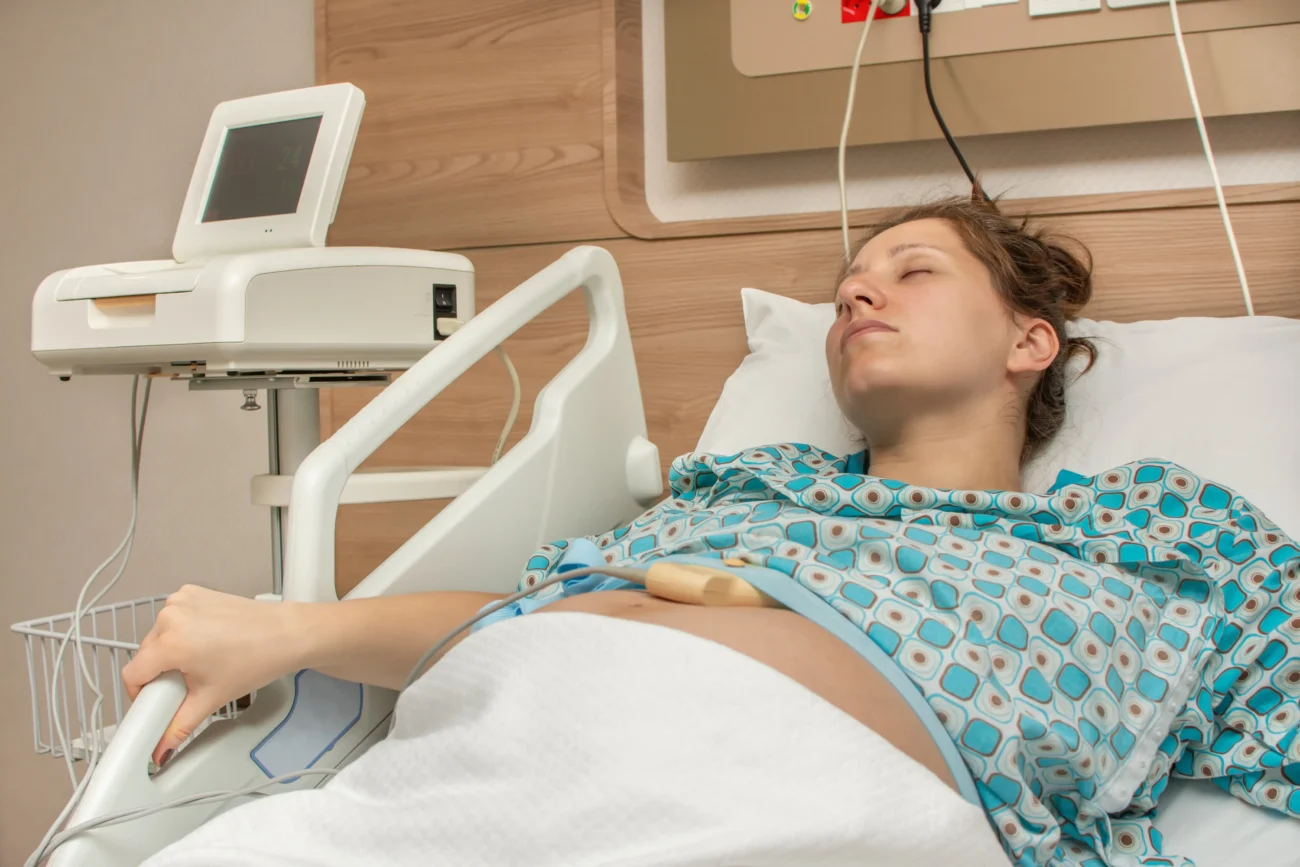 Žena leží v nemocnici na lůžku. 