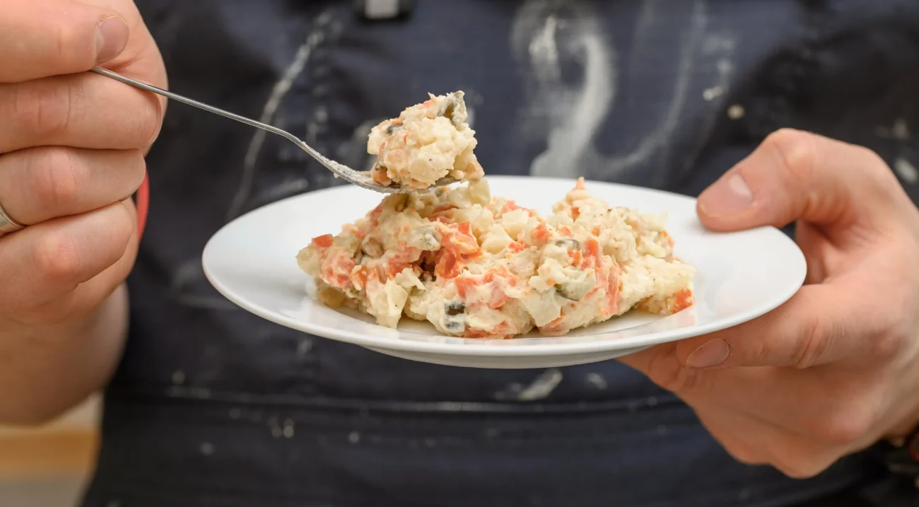 shutterstock_2591986329-2 | TVGURU.cz Muž si vidličkou nabírá bramborový salát.