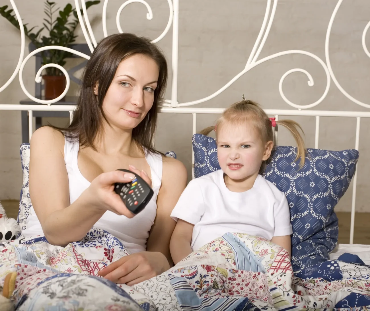 Žena s holčičkou sedí na posteli a tváří se překvapeně.