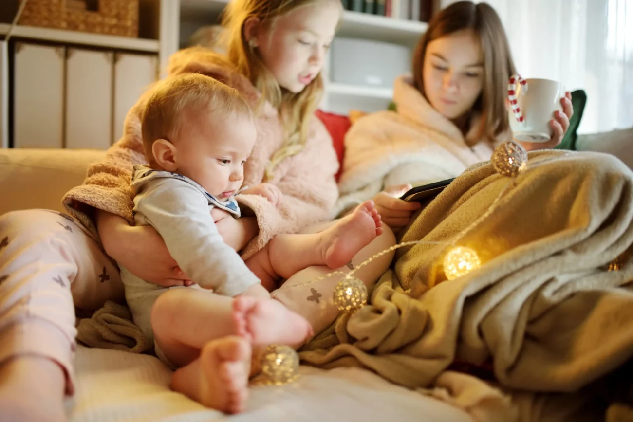 Holčičky sedí na gauči a jsou na telefonu. 