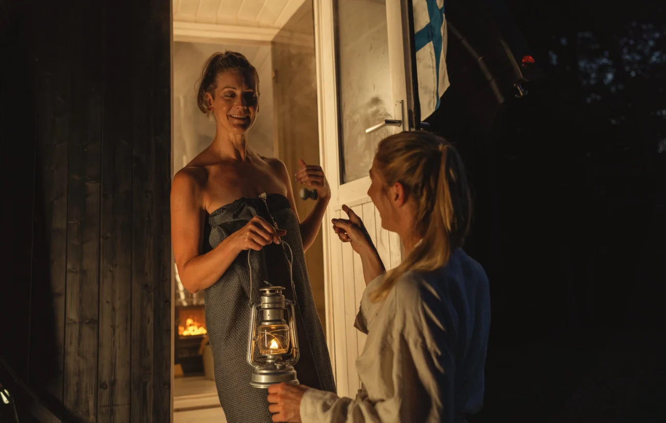 Ženy stojí mezi dveřmi do sauny a povídají si.