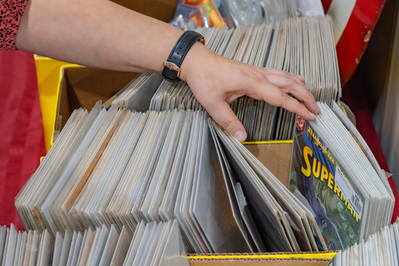 Člověk se přehrabuje krabicí plnou komiksů.